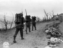 sc 374760   past some strewn about german equipment  and a dead german soldier that someone thoughtfully covered up  go three men carrying howitzer ammunition tmd mt. belvedere area  italy. 21 02